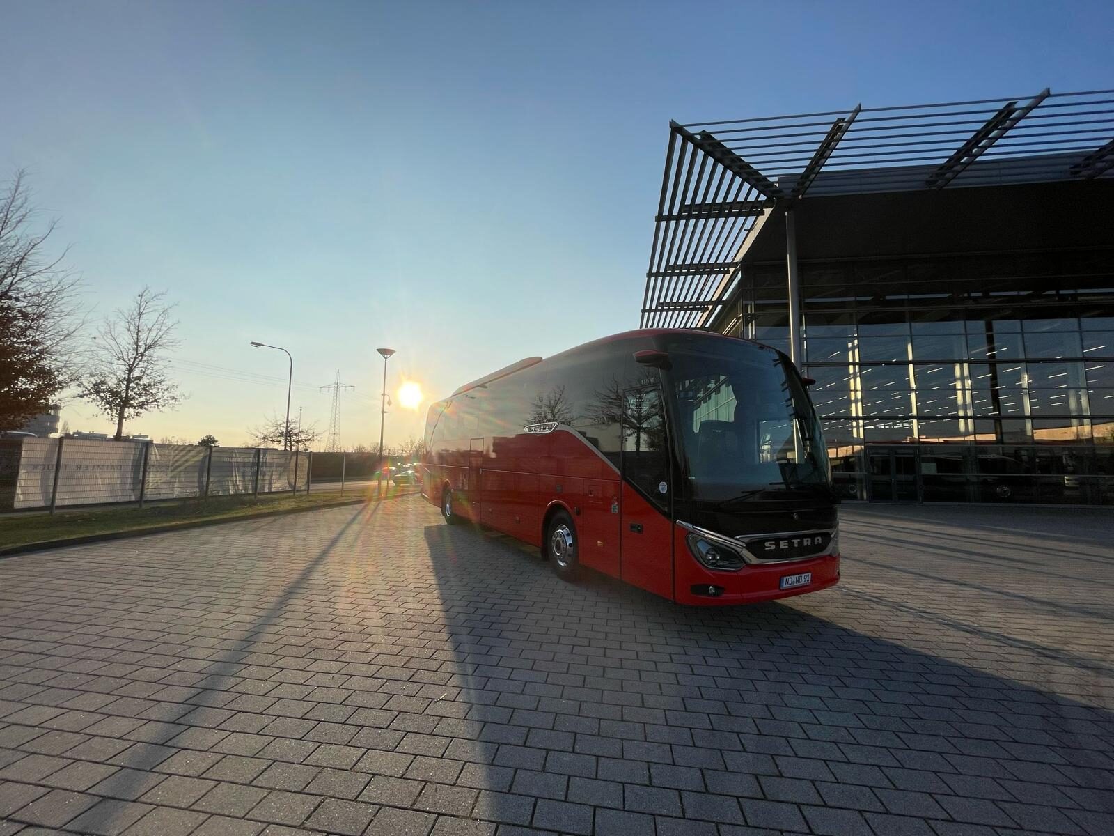 Setra-Reisebus Donaumoos Reisen im Sonnenuntergang vor moderner Halle